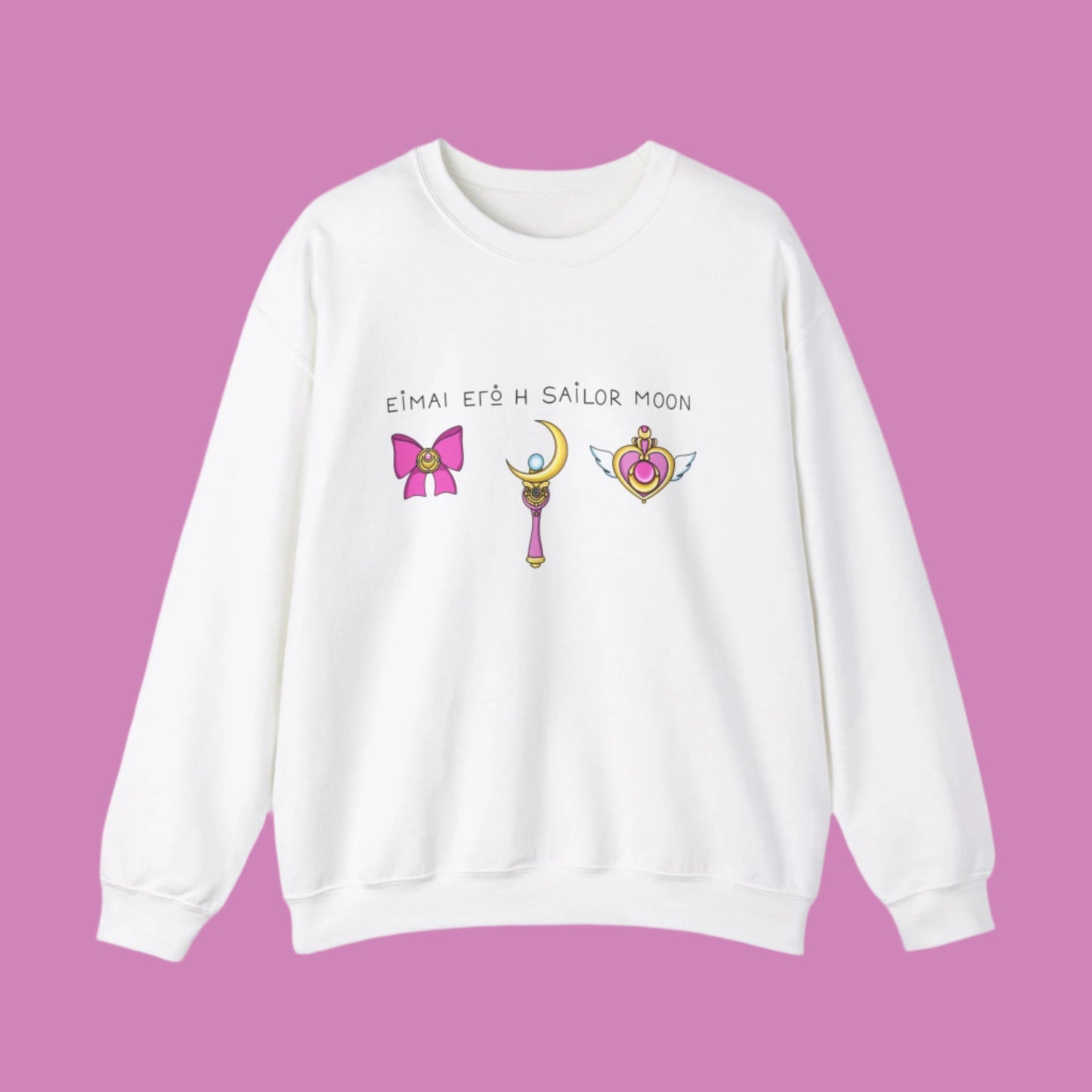 White sweatshirt featuring a Greek text on the chest 'Ειμαι εγώ η Sailor Moon'. Below the text is an illustration of Sailor Moon's signature items in pink tones: a ribbon, moon stick, and a heart.
